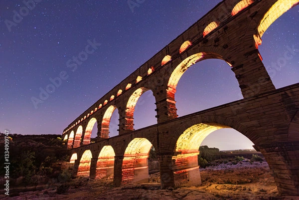 Obraz Pont du Gard, ancient Roman aqueduct bridge, colorful projection mapping video show, under Provence starry night sky, Gorges du Gardon, natural landscape designated Biosphere Reserve by UNESCO, France