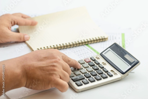 Fototapeta Hand pressing buttons on calculator while preparing financial reports in an office setting