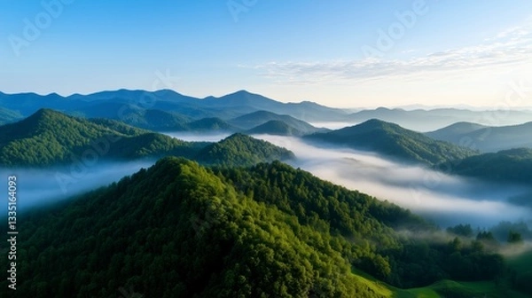 Obraz Morning fog blankets rolling hills in a serene mountainous landscape at sunrise