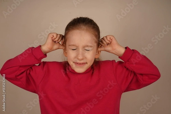 Fototapeta It s a moment of frustration and sensitivity to sound. The girl covers her ears with her fingers, her eyes tightly shut. Her expression shows discomfort and a desire to block out unwanted noise.