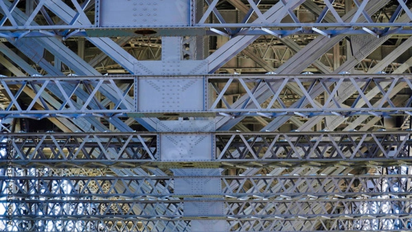 Fototapeta Detailed view of intricate steel lattice structure beneath a major bridge showcasing engineering excellence and design precision
