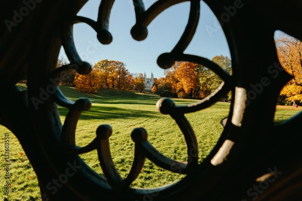 Fototapeta View of the autumn trees through the Gothic ornament of the ancient well, the Gothic church in the park. Autumn in a public park