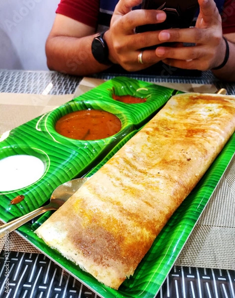 Fototapeta South indian food crispy Masala Dosa with sambar and chutney on banana leaf style plate