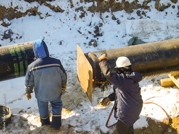 Fototapeta The workers engaged in the construction of the pipeline. Welders build the pipeline. Installation work in the construction and installation of the pipeline