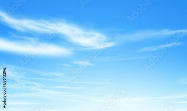 Fototapeta A bright, clear sky with soft white clouds drifting lightly across the vast blue expanse above the horizon