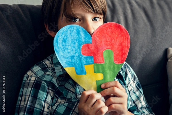 Fototapeta Child with autism holds in his hands the heart of puzzles, as a symbol of autism. World Autism Awareness Day. Boy Autist.