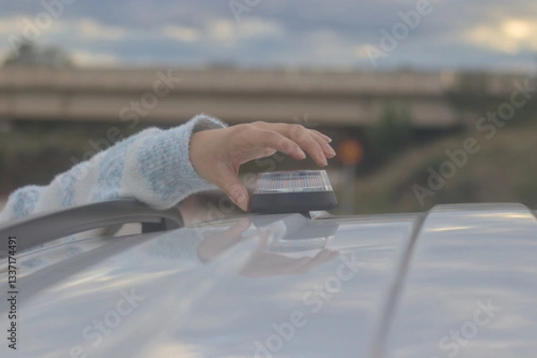 Obraz Hand placing a V16 emergency beacon on the roof of a broken-down vehicle. The emergency flasher is mandatory for replacing triangles in Europe. DGT Spain.