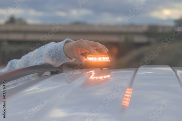 Obraz Hand placing a V16 emergency beacon on the roof of a broken-down vehicle. The emergency flasher is mandatory for replacing triangles in Europe. DGT Spain.