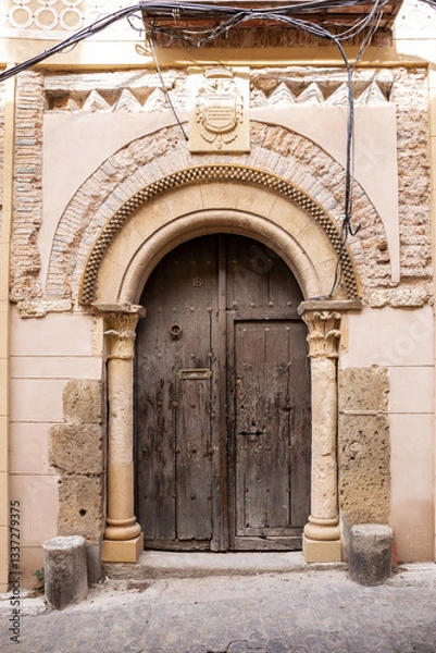 Fototapeta Old, medieval wooden doors with stone carved arches and coat of arms above in Segovia, Spain.