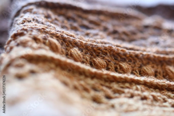 Fototapeta Close-up shot of a knitted blanket on a bed, perfect for lifestyle and home decor content.