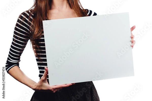 Fototapeta Long-haired beautiful cute brunette woman holding a rectangular blank-poster. white canvas with space for text.