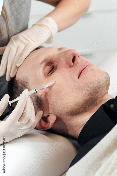Fototapeta Master performs facial mesotherapy on a man