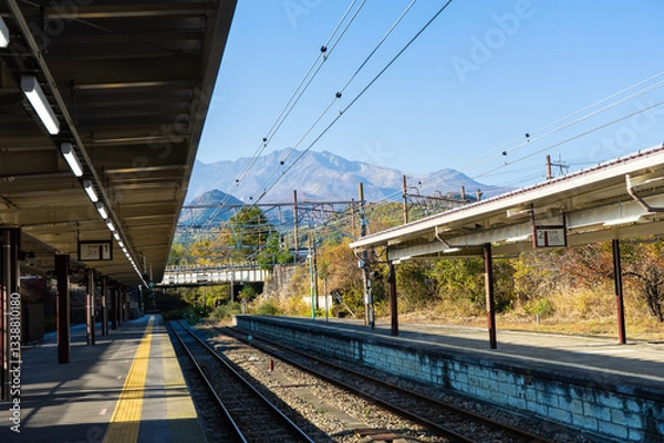 Fototapeta A quiet train station at the foot of the mountain
