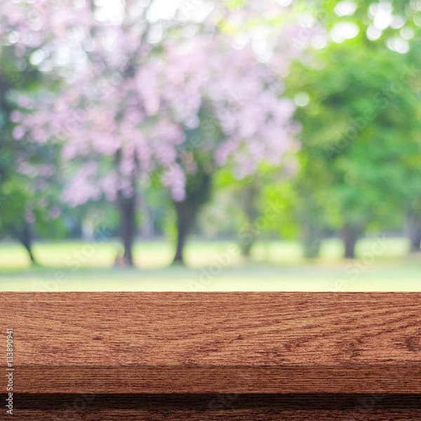 Fototapeta Empty wooden table over blurred tree with bokeh background