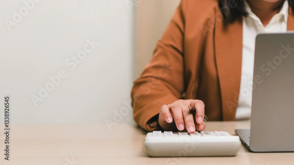 Fototapeta Financial accounting and business budgeting concept. Professional calculating business expenses with calculator and laptop, illustrating finance management, audit, and economic planning.