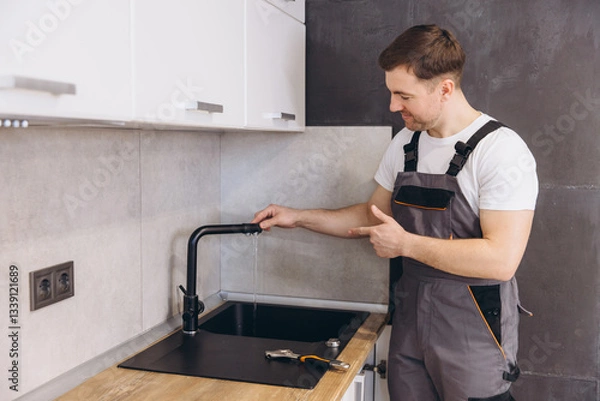 Fototapeta Plumber checking running water in kitchen sink