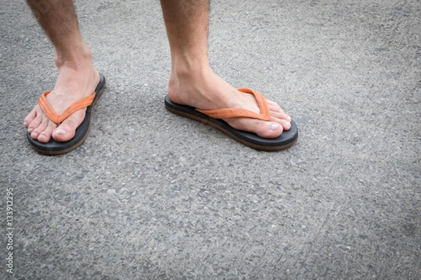 Obraz Feet of a man wearing sandals on the old concrete floor.