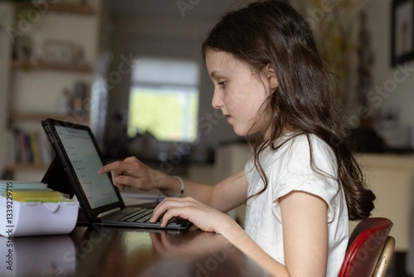 Fototapeta Mädchen, 10 Jahre, sitzt mit Tablet am Tisch und lernt