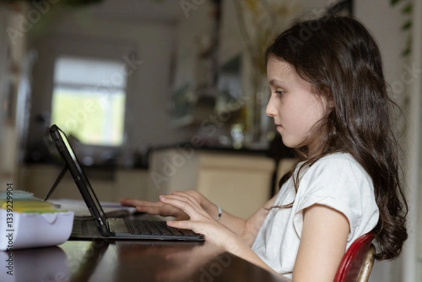 Fototapeta Mädchen, 10 Jahre, sitzt mit Tablet am Tisch und lernt