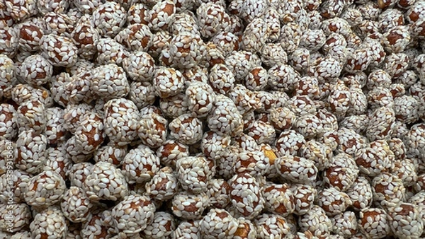 Fototapeta Sesame-coated peanuts lie in a random order on the display case.