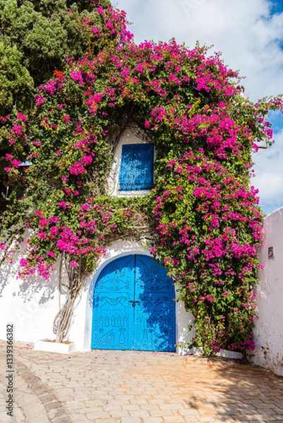 Fototapeta One of the typical blue and white houses with a large bourganvillea climber bush at the UNESCO World Heritage site of Sidi Bou Said, Tunis, Tunisia