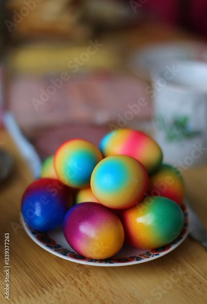 Fototapeta Multicolored Easter eggs lying on a plate and a wooden table