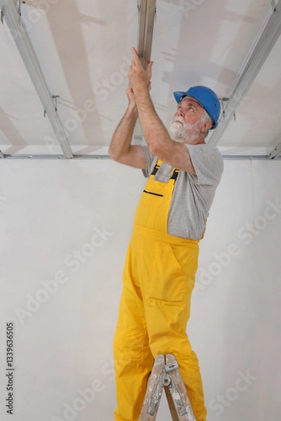 Obraz Senior adult worker fixing aluminum batten for gypsum ceiling