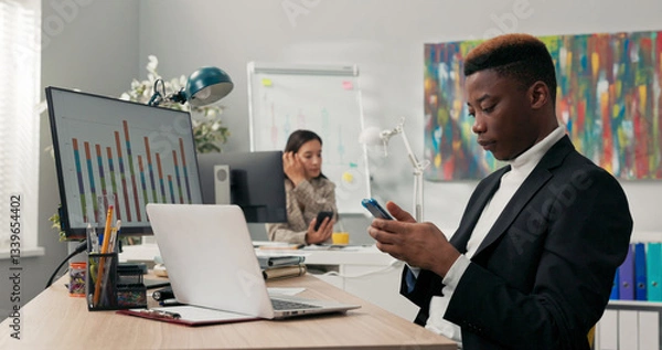Fototapeta Office workers sit at their desks in front of computer monitors, not attending to their duties, using phones, browsing social media, chatting with friends, a break from work