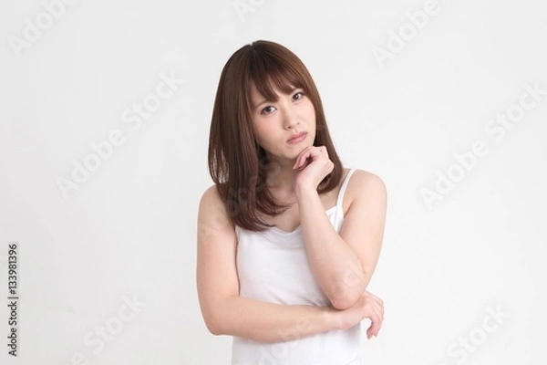 Obraz 若い女性が、疑問や悩みがあるようなポーズをしています。この画像の背景は、白です。