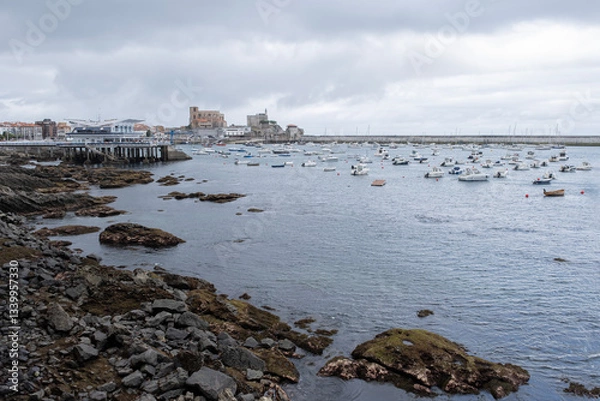 Fototapeta Panoramic view of Castro Urdiales, in Cantabria, with its breakwater in the background and its marina with a multitude of boats anchored in the foreground