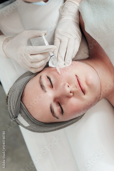 Obraz The beautician at the salon performs mesotherapy with a syringe in the facial area for a young female client