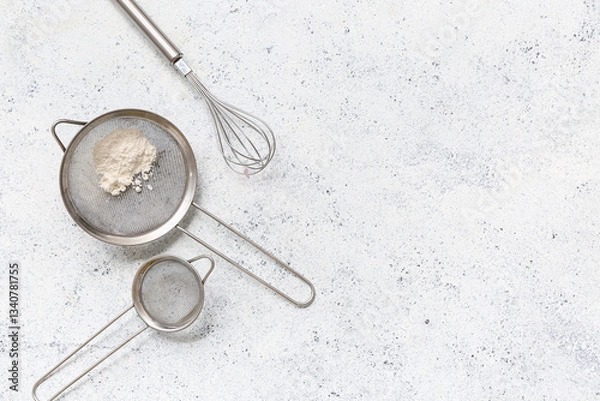 Fototapeta Metal sieves with flour and whisk on light background