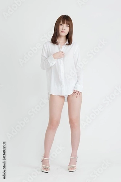 Obraz 白いシャツを着た女性。女性は足の素肌を見せています。スタジオ撮影。白背景。