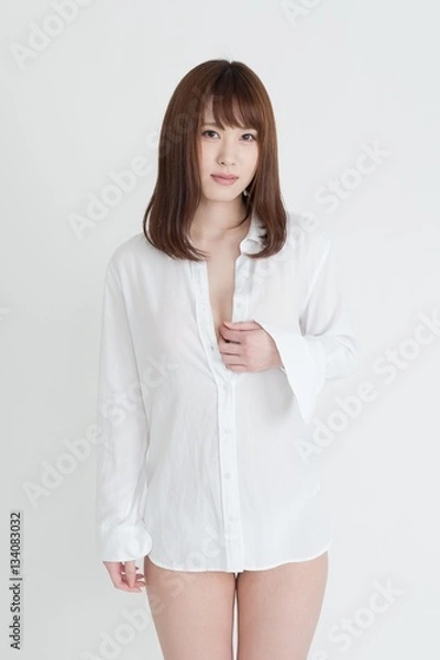 Obraz 白いシャツを着たセクシーな女性。この女性は、脚の素肌を見せています。スタジオ撮影。白背景。
