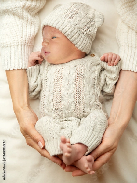 Fototapeta Baby lying on Blanket in Mother Hands. Mum Love. Newborn sleep in woolen Bodysuit in Parent embrace. Infant Clothes. Little Child Development