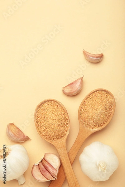 Fototapeta Fresh garlic and garlic powder on spoon on beige background. Using spices for meals. Top view