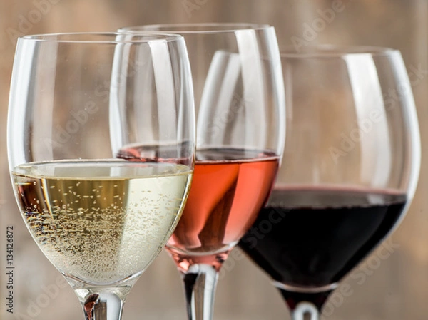 Obraz Glasses of red, white and rose wine on a wood background