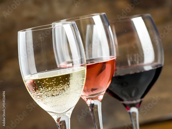Obraz Glasses of red, white and rose wine on a dark wood background