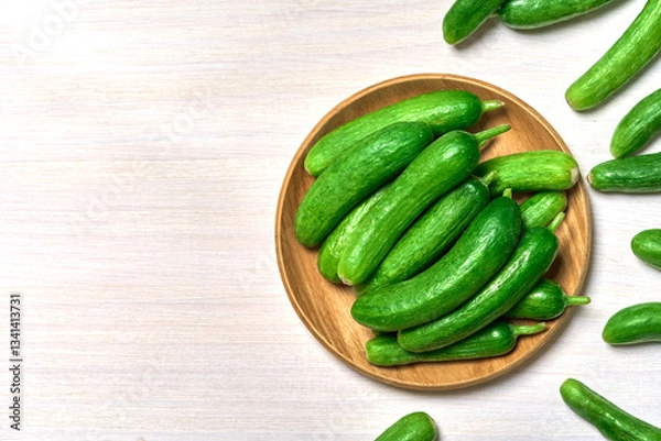 Fototapeta top view flat lay pile of Dutch holland green cucumber in wood bowl on white wooden table background with copy space