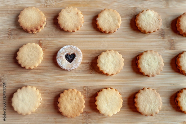 Fototapeta Homemade round shortbread cookies placed in a rows on bamboo plank. One of them is different.