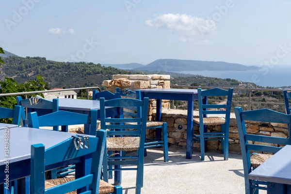 Fototapeta Tables and chairs of an outdoor tavern with a view of the mountains and the sea close-up
