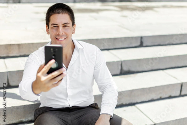 Fototapeta Successful businessman taking a selfie with a modern skyline in the background. copyspace