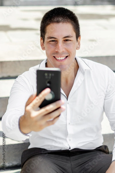 Fototapeta Successful businessman taking a selfie with a modern skyline in the background