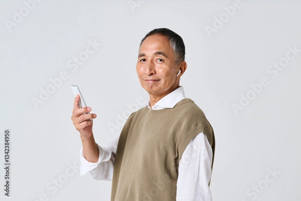 Fototapeta スマートフォンで音楽を聴く私服姿のシニア男性