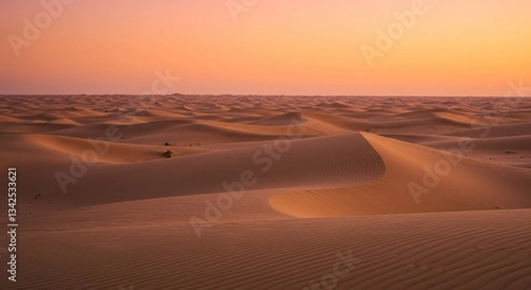 Fototapeta Endless sand dunes under a twilight sky. Warm orange and pink hues blend softly with the desert landscape, with rippled sand patterns adding texture