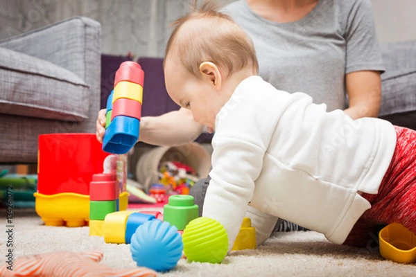 Obraz Nine months old baby girl playing with her toys on the floor and