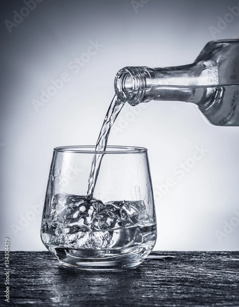 Obraz Pouring alcohol into a glass. Monochrome picture.