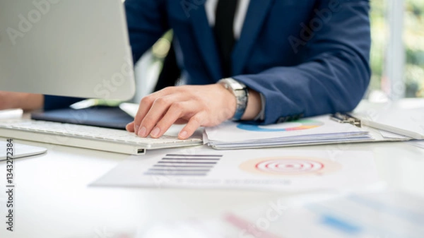 Fototapeta Closeup of businessman or office worker typing on computer keyboard while putting arm on file folder
