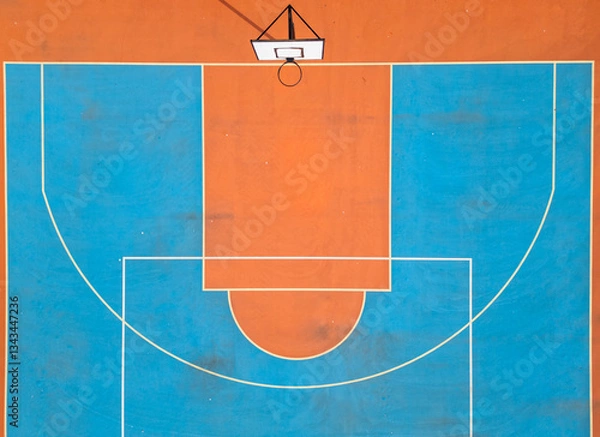 Fototapeta Aerial view of a basketball hoop and colorful court with vibrant orange and blue sections. The symmetrical layout and bold colors create a striking sports-themed composition