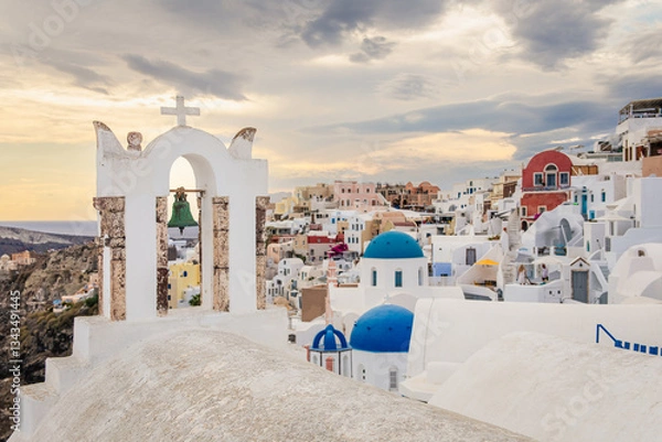 Fototapeta Scenic view of Oia, Santorini, Greece, featuring the iconic three domes viewpoint, colorful houses, and the Aegean Sea. Horizontal shot with a cloudy sky, perfect for honeymoon or wedding destination